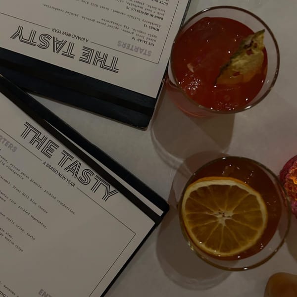 Two menus for The Tasty restaurant and two cocktails, one garnished with an orange slice.